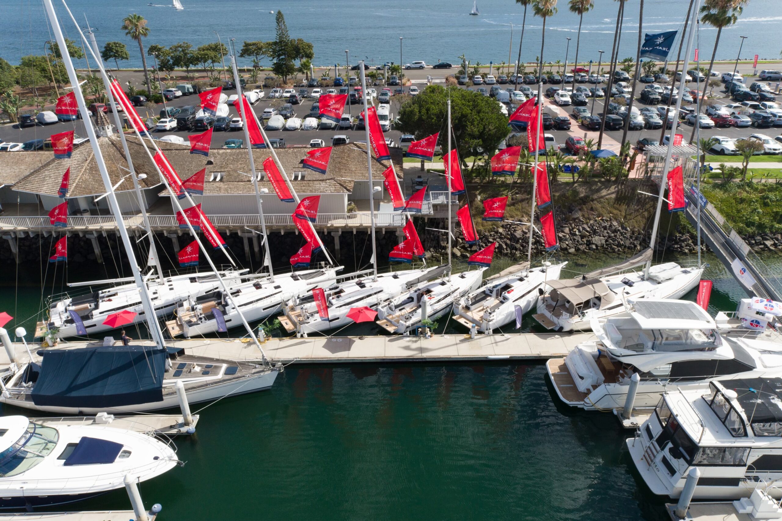 jeanneau sailboats in a marina with red flags